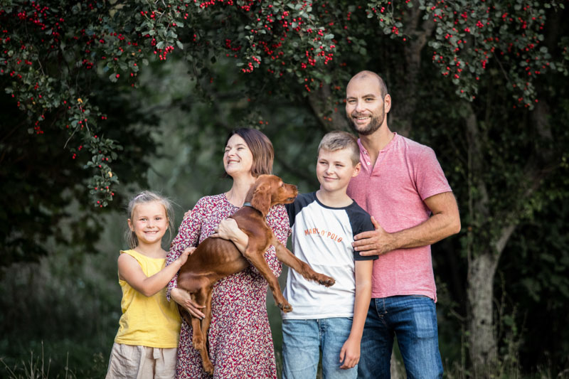 Familienbild in der Natur bestehend aus den Eltern, zwei Kindern und einem Hundewelpen