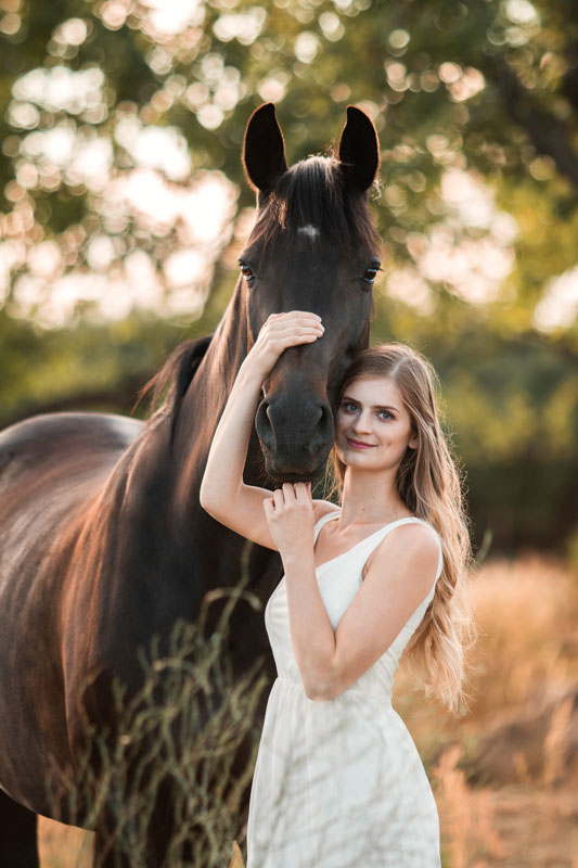 Besitzerin mit ihrem Pferd im Abendlicht im Portrait